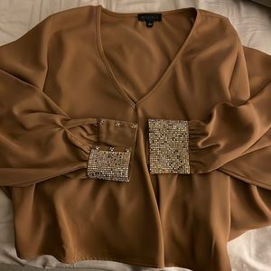 Tan, cropped blouse, with cinched wrist with gold jewels at wrist. Unique cut